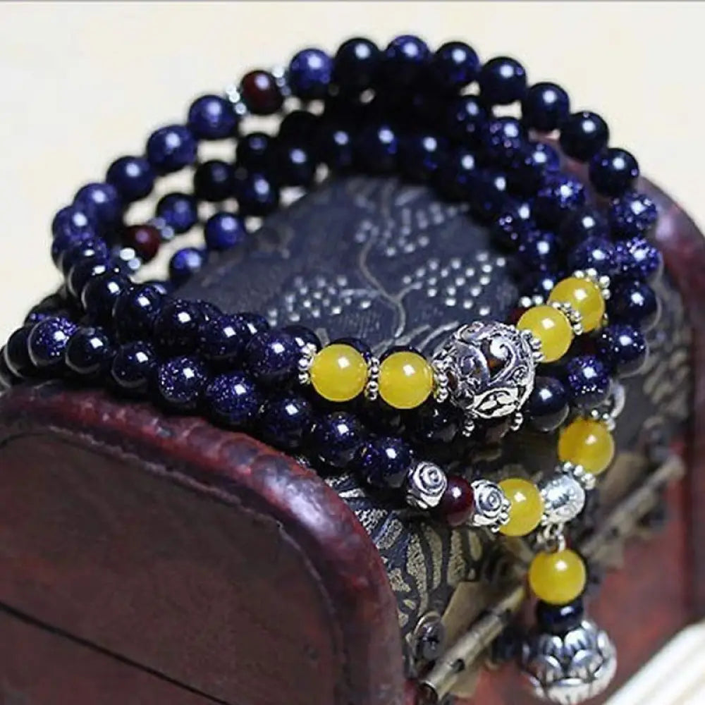 BWOOOH Blue Sandstone Wealth Charm Mala. Deep blue 6mm beads with sparkling inclusions, mimicking a starry night. Promotes courage, calm, and wealth for focused meditation.
