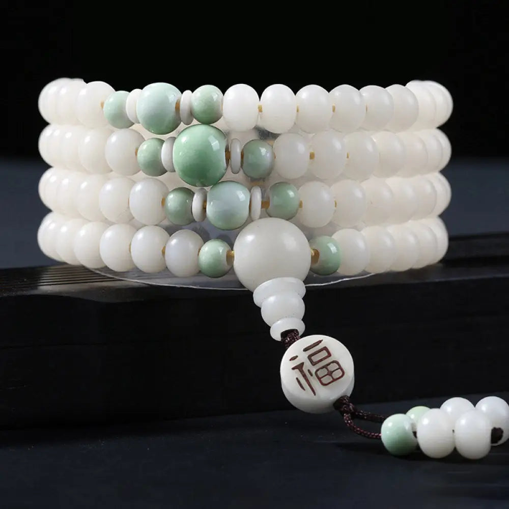 A close-up of the BWOOOH Bodhi Seed Lotus Blessing Charm Bracelet, featuring naturally dark-speckled bodhi seed beads alongside a delicate lotus symbol charm, suitable for unisex wear. - View 8