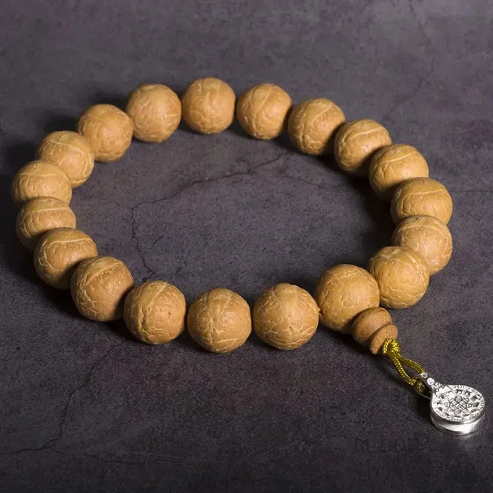 Close-up of BWOOOH Bodhi Seed Wrist Mala featuring dark-speckled 13mm/15mm bodhi seeds on premium elastic string, with a delicate tassel, worn as a meditation accessory or carried as a pocket mala. Unisex. - View 4