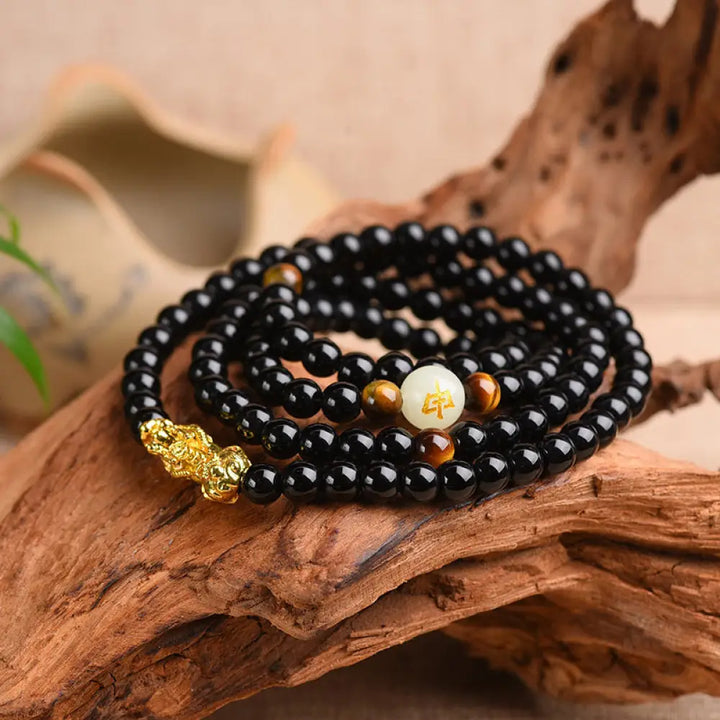 A close-up of the BWOOOH Unisex Chinese Zodiac Obsidian PiXiu Protection Mala Bracelet featuring polished black 6mm or 8mm obsidian beads and a detailed PiXiu charm, designed for spiritual grounding and attracting prosperity.