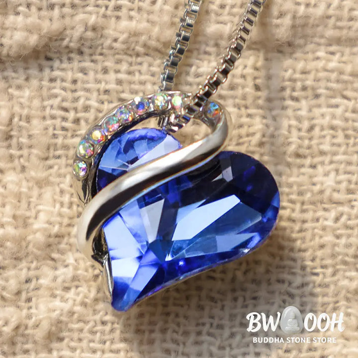 A BWOOOH Love Heart Birthstone Necklace pendant featuring a vibrant, wild-heart-shaped premium crystal, elegantly embraced by a silver-tone ribbon forming an infinity symbol, symbolizing triumph of love and eternal spiritual connection. - View 13