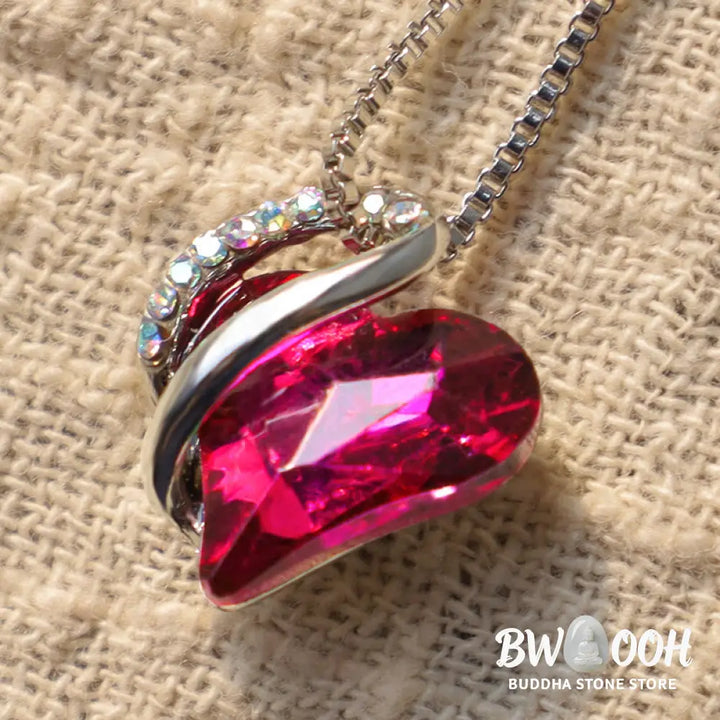 A BWOOOH Love Heart Birthstone Necklace pendant featuring a vibrant, wild-heart-shaped premium crystal, elegantly embraced by a silver-tone ribbon forming an infinity symbol, symbolizing triumph of love and eternal spiritual connection. - View 9