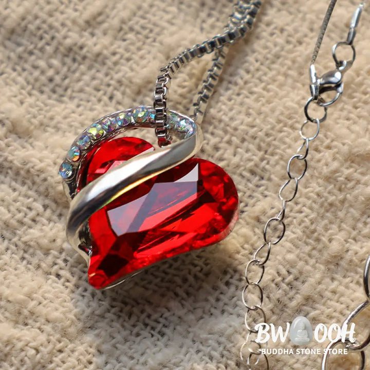 A BWOOOH Love Heart Birthstone Necklace pendant featuring a vibrant, wild-heart-shaped premium crystal, elegantly embraced by a silver-tone ribbon forming an infinity symbol, symbolizing triumph of love and eternal spiritual connection. - View 5