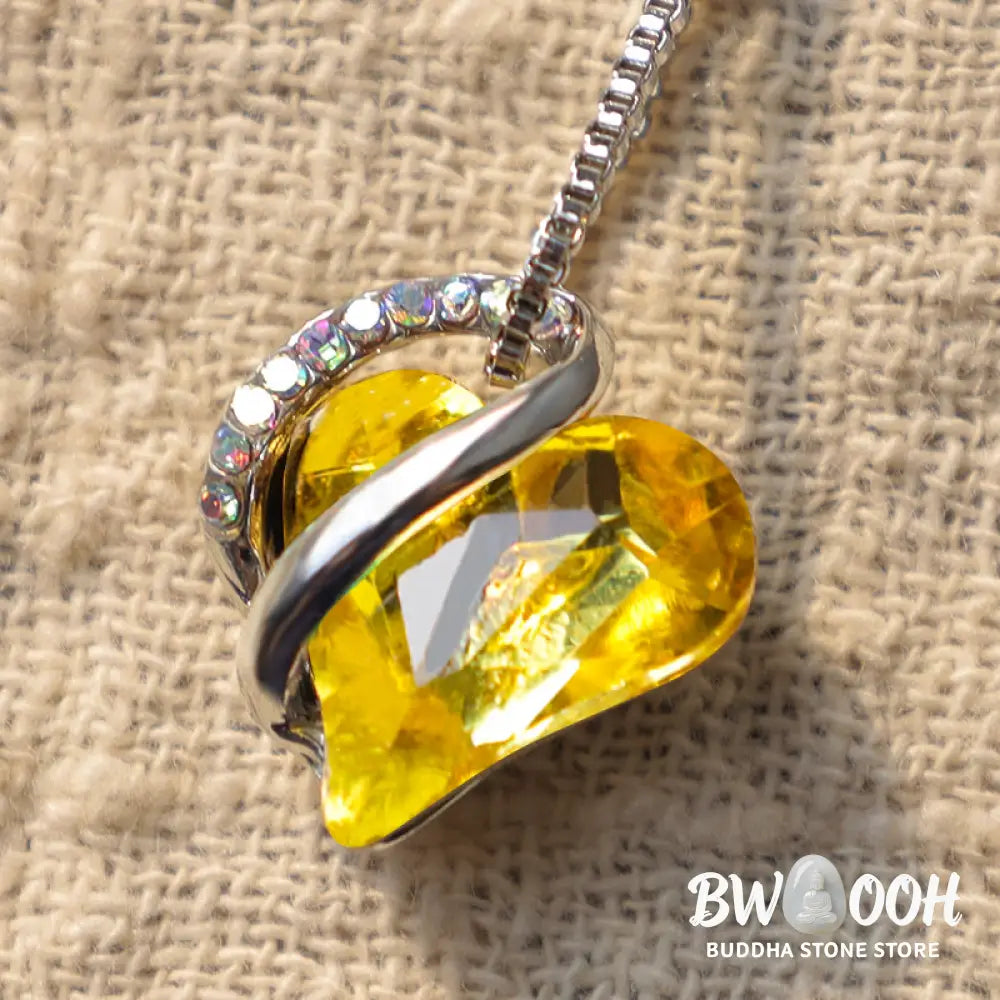 A BWOOOH Love Heart Birthstone Necklace pendant featuring a vibrant, wild-heart-shaped premium crystal, elegantly embraced by a silver-tone ribbon forming an infinity symbol, symbolizing triumph of love and eternal spiritual connection. - View 39