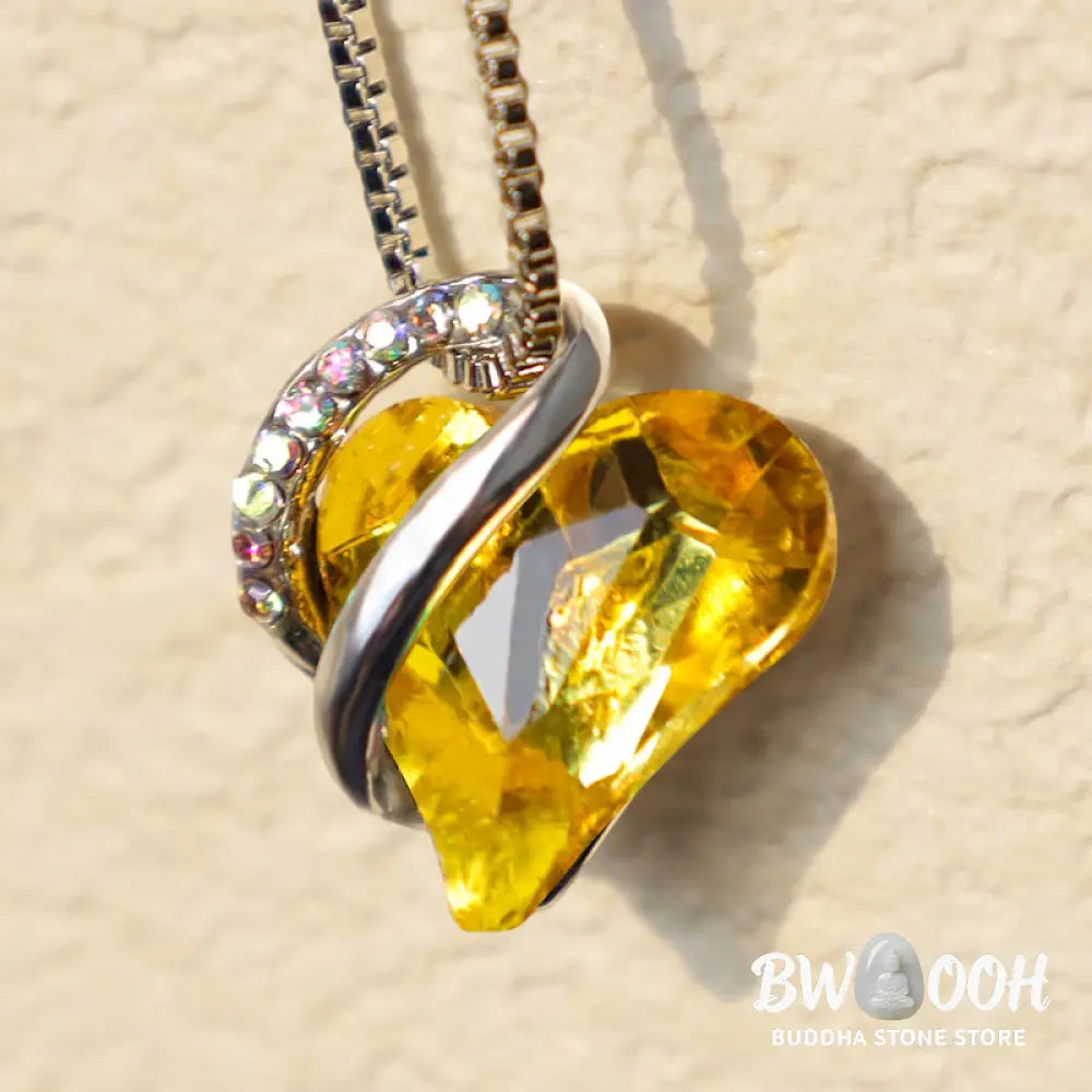 A BWOOOH Love Heart Birthstone Necklace pendant featuring a vibrant, wild-heart-shaped premium crystal, elegantly embraced by a silver-tone ribbon forming an infinity symbol, symbolizing triumph of love and eternal spiritual connection. - View 40