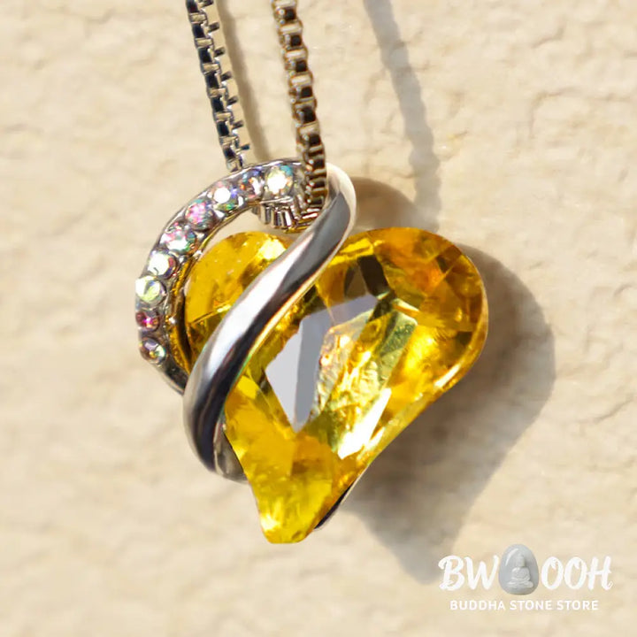 A BWOOOH Love Heart Birthstone Necklace pendant featuring a vibrant, wild-heart-shaped premium crystal, elegantly embraced by a silver-tone ribbon forming an infinity symbol, symbolizing triumph of love and eternal spiritual connection. - View 40