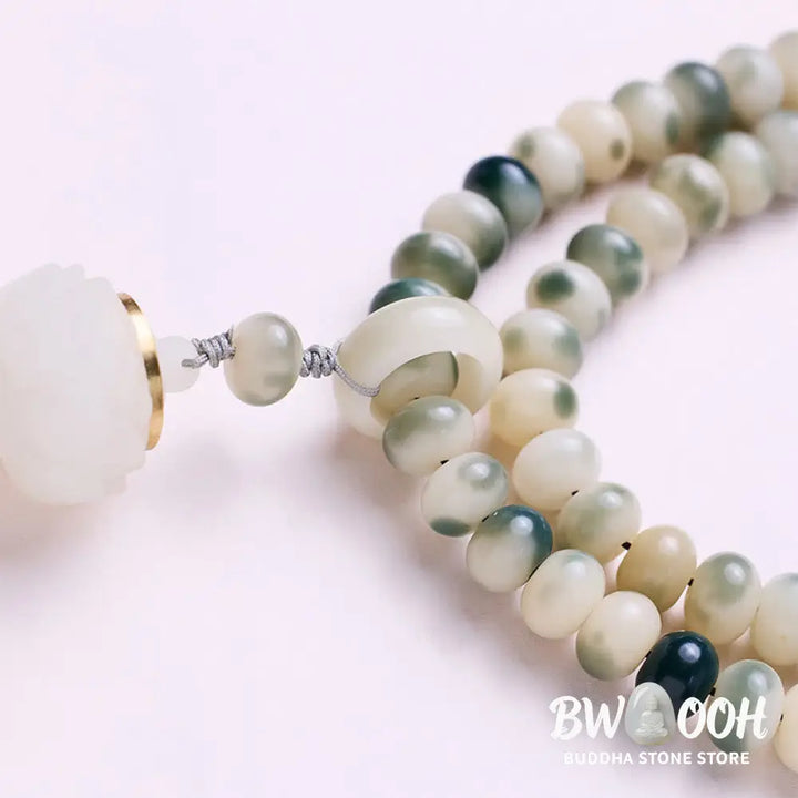 BWOOOH Natural 108 Bodhi Seed Mala Bracelet with carved lotus, luminous stone accents, and a wisdom tassel, displayed against a serene backdrop, ready for mindful practice. - View 5