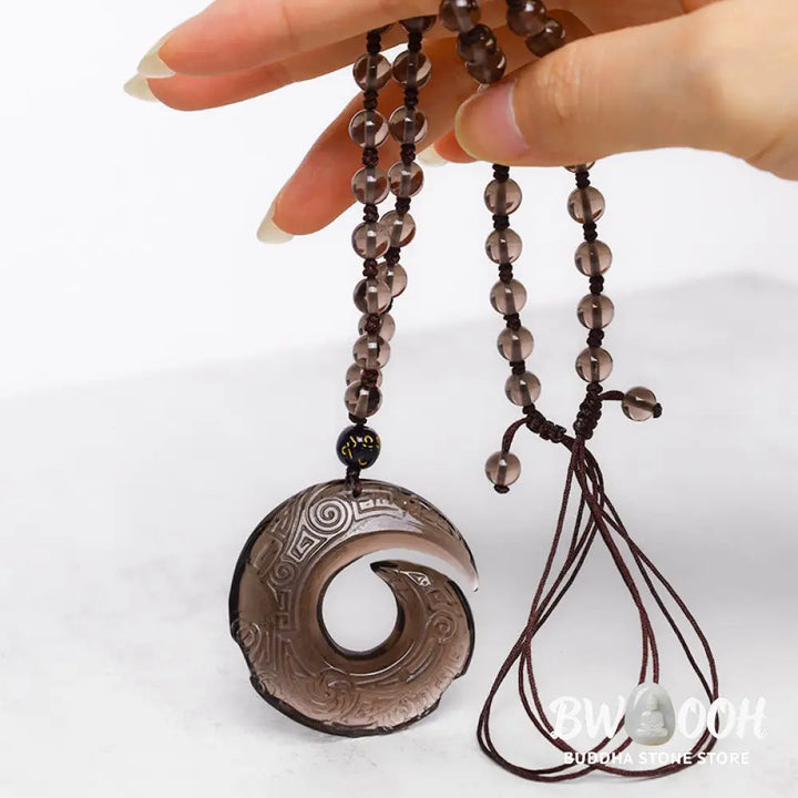 BWOOOH Natural Black Obsidian and Ice Obsidian Peace Buckle Strength Necklace Pendant, showcasing a polished black obsidian stone adjacent to a translucent ice obsidian peace buckle on an adjustable cord. - View 8