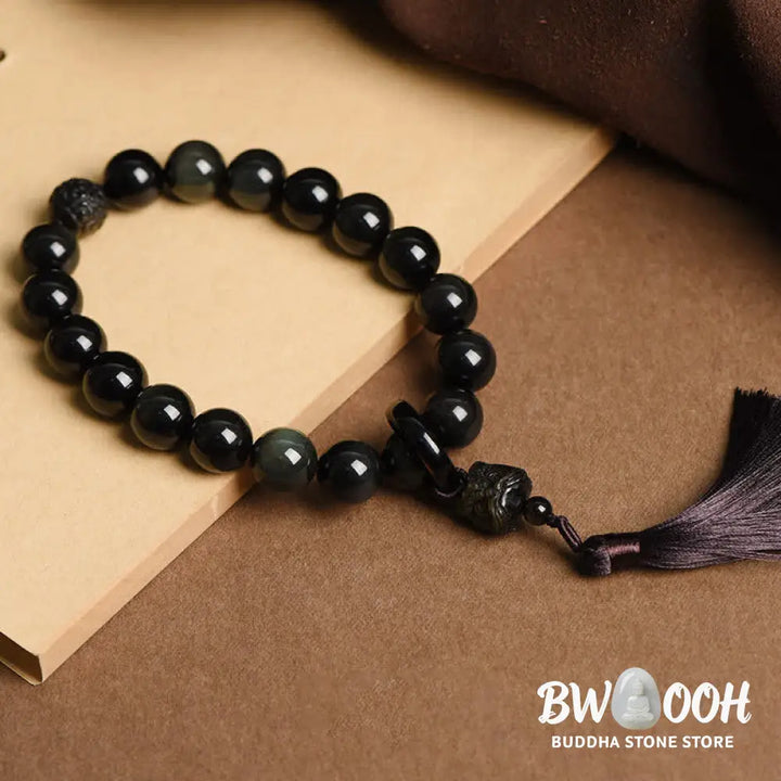 A BWOOOH Natural Black Obsidian Lion Wrist Mala with protection tassels, shown as a pocket mala and car decoration, embodying courage, wisdom, and spiritual enlightenment for energetic protection and positive Feng Shui. - View 2