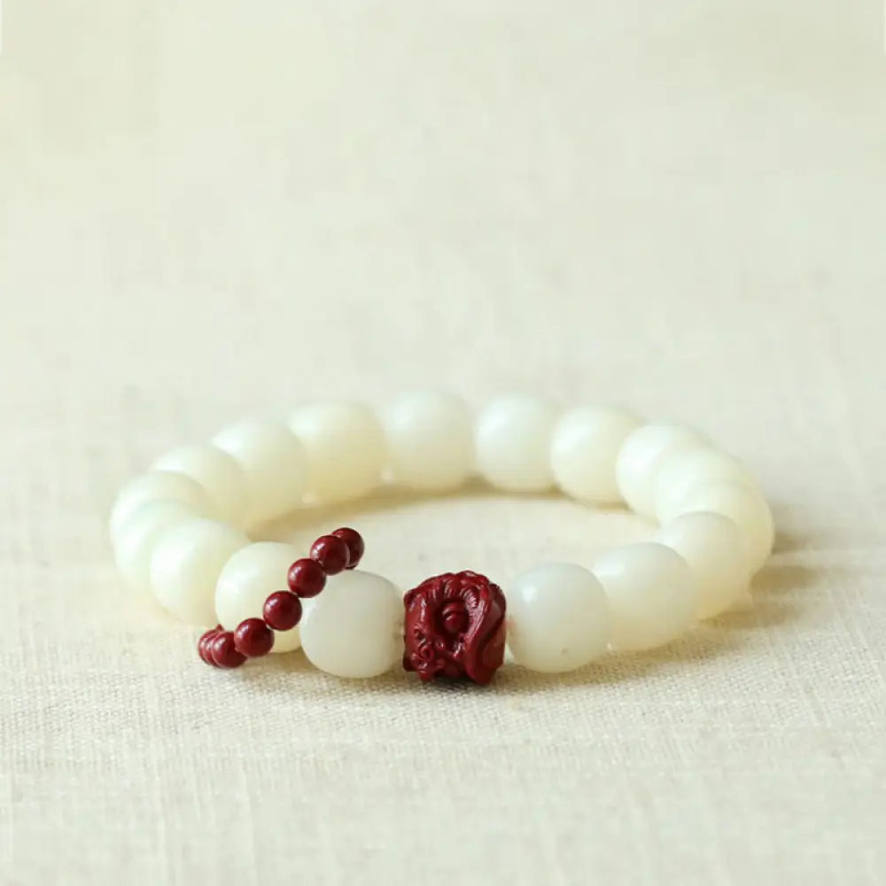 Close-up of BWOOOH Natural Bodhi Seed Wrist Mala with vibrant red Cinnabar beads and a detailed Dancing Lion charm on an elastic string, symbolizing wisdom, harmony, and protection during meditation practices.