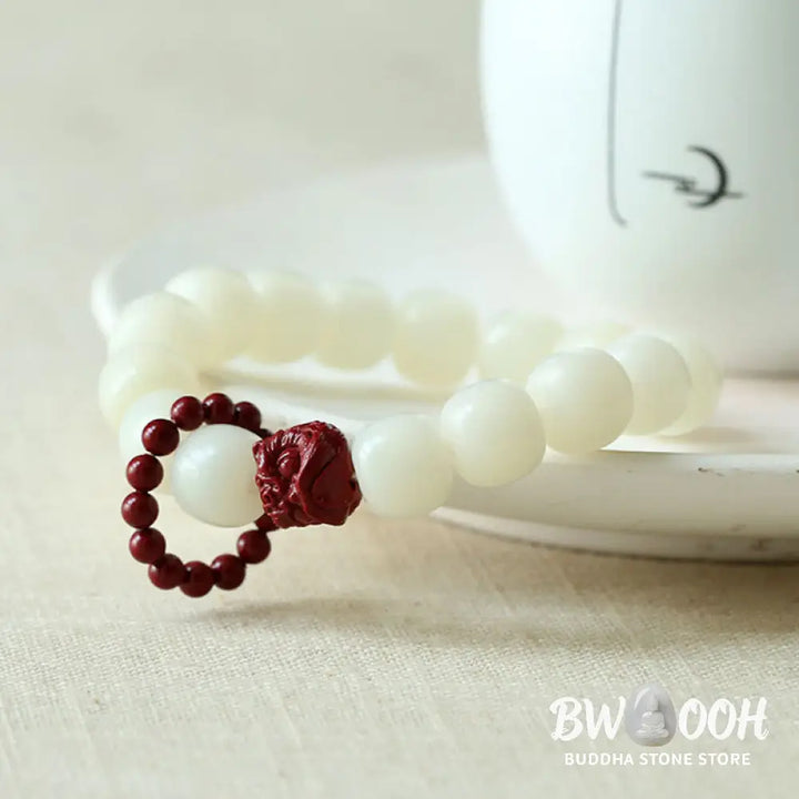 Close-up of BWOOOH Natural Bodhi Seed Wrist Mala with vibrant red Cinnabar beads and a detailed Dancing Lion charm on an elastic string, symbolizing wisdom, harmony, and protection during meditation practices. - View 3