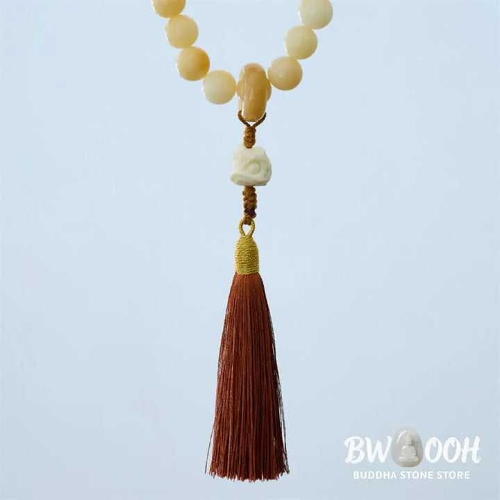A close-up of the BWOOOH Natural Bodhi Seed Ivory Fruit Dancing Lion Charm Harmony Tassel Wrist Mala, featuring 12mm dark-speckled Bodhi Seed beads, smooth Ivory Fruit accents, and a detailed golden Dancing Lion charm with a vibrant harmony tassel, set against a muted, calming background. - View 6