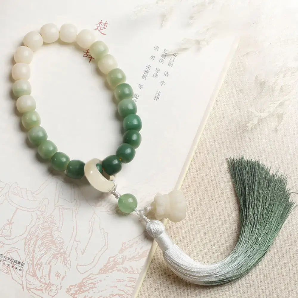 BWOOOH Natural Gradient Bodhi Seed Fortune Money Bag Lotus Wisdom Tassel Wrist Mala featuring 12mm dark-speckled bodhi seeds, boxwood, agate, and green aventurine; a handcrafted spiritual meditation bracelet for wisdom and calm.