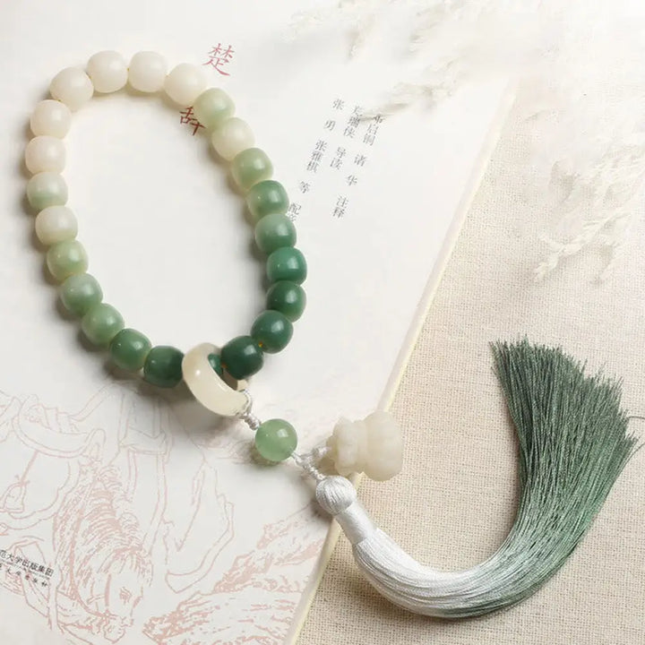 BWOOOH Natural Gradient Bodhi Seed Fortune Money Bag Lotus Wisdom Tassel Wrist Mala featuring 12mm dark-speckled bodhi seeds, boxwood, agate, and green aventurine; a handcrafted spiritual meditation bracelet for wisdom and calm.