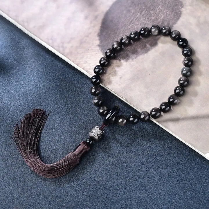 BWOOOH Silver Sheen Obsidian Lion Wrist Mala, polished beads (12-16mm), carved lion, tassels. Offers energetic protection, also a pocket mala or car decoration. - View 2