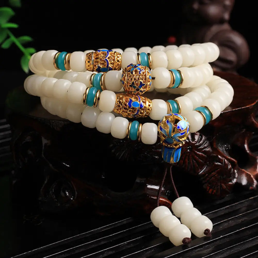 A BWOOOH Natural White Bodhi Seed Mala bracelet, featuring 108 dark-speckled beads, handmade for meditation, spiritual wisdom, and attracting wealth. Unisex design, worn on wrist.