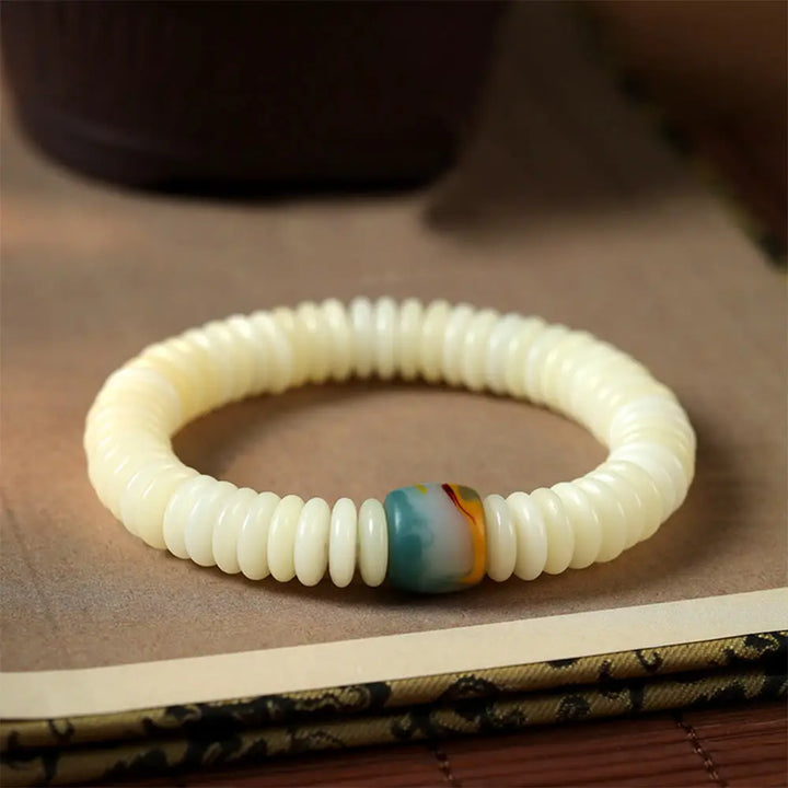 BWOOOH Natural White Bodhi Seed Wisdom Tassel Wrist Mala Bracelet, featuring dark-speckled Bodhi seeds (3x10mm) with a white copper accent and soft tassel, on a 14-15cm elastic string. Ideal for meditation and spiritual balance.