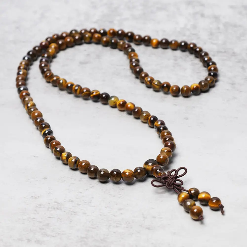 BWOOOH Tibetan 108-bead natural Tiger Eye gemstone prayer mala, handcrafted as a spiritual protection bracelet and necklace, coiled to showcase polished beads.
