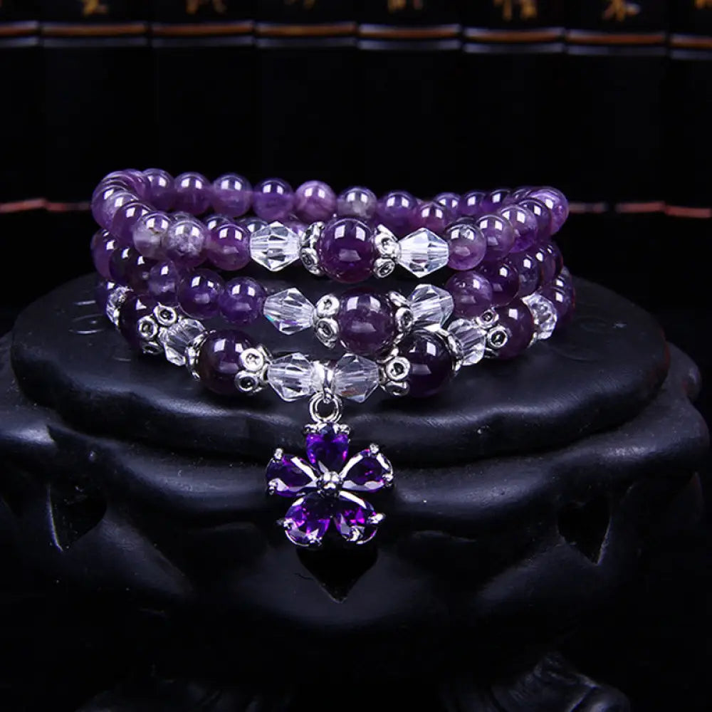 A close-up of the BWOOOH handcrafted Tibetan Amethyst Blessing Bracelet featuring lustrous 6mm natural purple amethyst beads and silver-plated copper accents, symbolizing spiritual protection and inner peace.