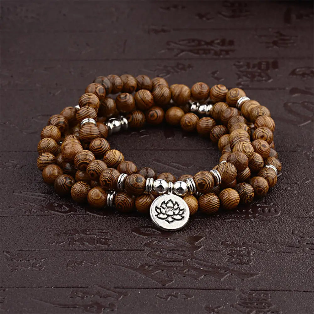 A BWOOOH Tibetan Lightning Strike Wood Mala Bracelet, 46cm circumference, featuring distinct lightning bolt markings, accented with a silver-colored Lotus symbol and a peaceful Buddha charm.