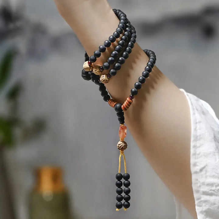 BWOOOH authentic Tibetan Mala bracelet or necklace crafted with 108 polished Cypress beads, distinctive dark-speckled Bodhi Seeds, vibrant Red Agate, and deep Garnet accents, embodying spiritual protection and healing energy.