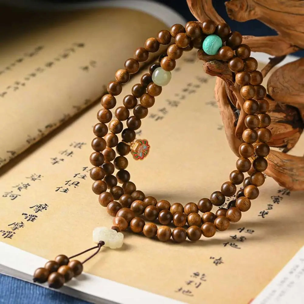 BWOOOH Tibetan Rosewood Protection Calm Bracelet Mala, 108 polished rosewood beads (6mm or 8mm) with red agate, green aventurine, turquoise, and jade accents, evoking protection and calm inspired by ancient Dzi traditions.